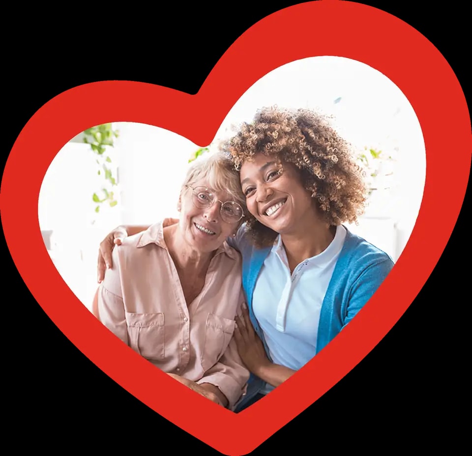 A caregiver and woman posing for a photo, smiling at the camera