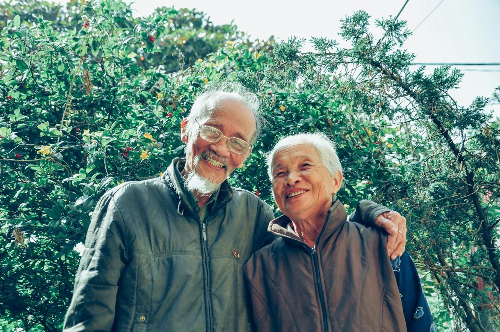 A happy older couple smiling together outdoors in a sunny green garden